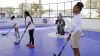 Kids in a street hockey rink  holding hockey sticks with a goalie in the background