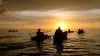 People in canoes and kayaks at sunset during a guided paddle at EG Simmons Conservation park