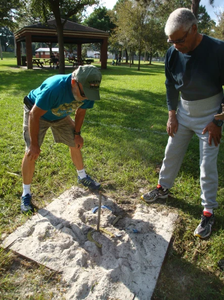 Two people checking out the horseshoes around the rod.