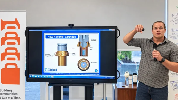 Garrett Waggoner stands next to a monitor with a slide describing how the cartridge of the Cirkul bottle works