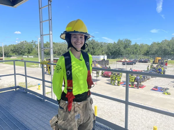 Ember Barakeh, stands in the training tower and below her are cadets in full ear looking at equipment
