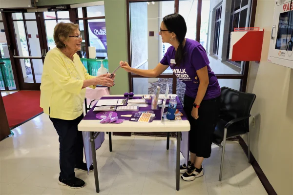 A woman hands a Alzheimer's Association pamphlet to another woman