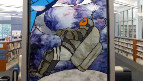 Stained glass - An astronaut floating above the surface of a gray planet