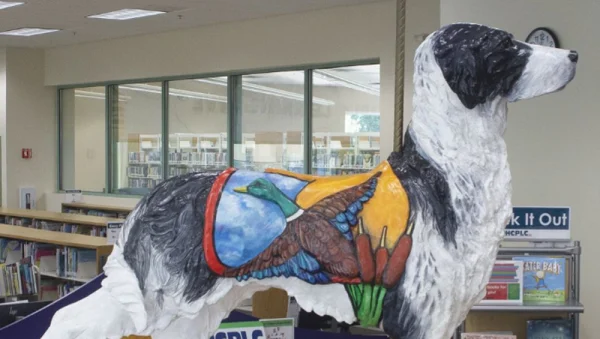 Sculpture - A black and white dog that does on a carousel - wearing a duck saddle