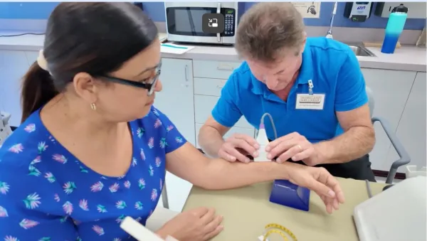 A technician uses a scanner to do a bone screening on a woman