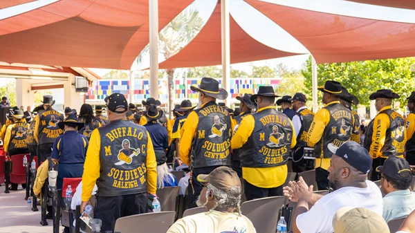 Audience members from the Buffalo Soldiers Florida Motorcycle Club wearing their vests are standing up