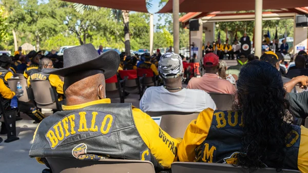 Men and women wearing Buffalo Soldier vests sit in the audience during the monument unveiling.