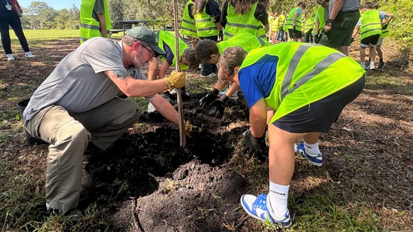 A Hillsborough County employee helps students plant a tree at Lake Park.