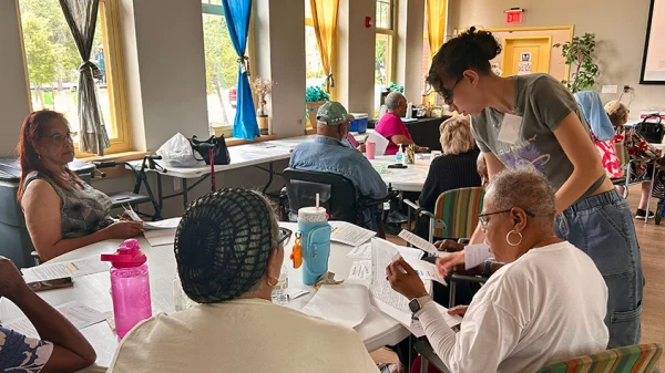 A woman is standing next to a table helping the students