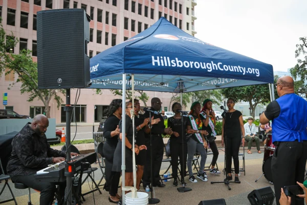 A choir performs under a Hillsborough County tent in front of the County Center building