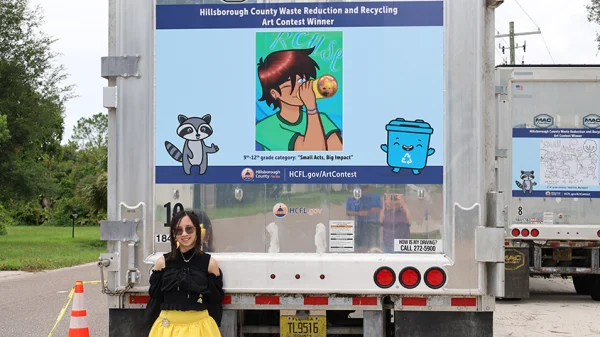 Kylee stands by the truck displaying her artwork with a them of Reuse.