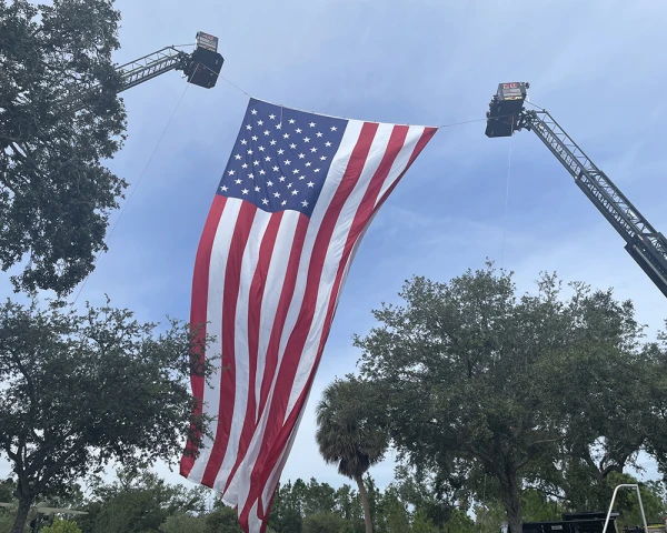 US flag hanging between to cranes