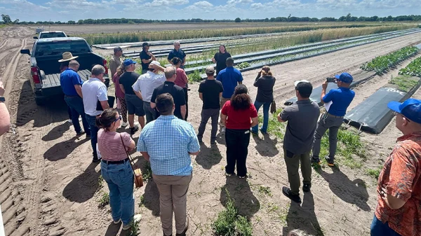 A group standing next to a crop listening to a staff member speak