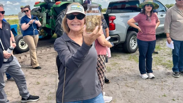 A woman holds a jar with roots in it up to the camera