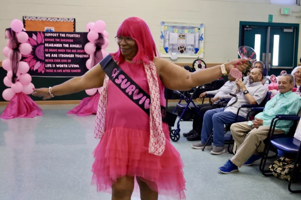 A woman with a breast cancer survivor sash dressed all in pink models a pink wig