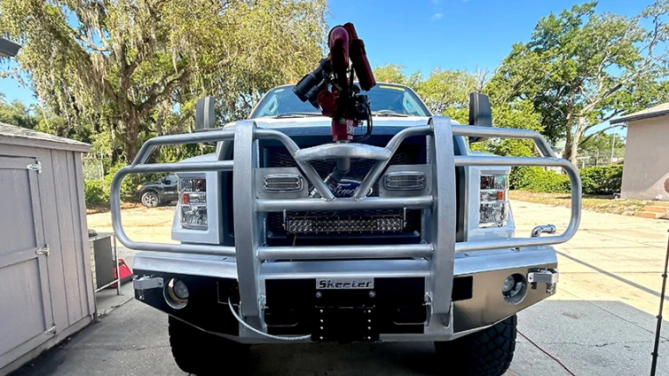 A close-up photo shows the grill and water fighting tools on the brush truck