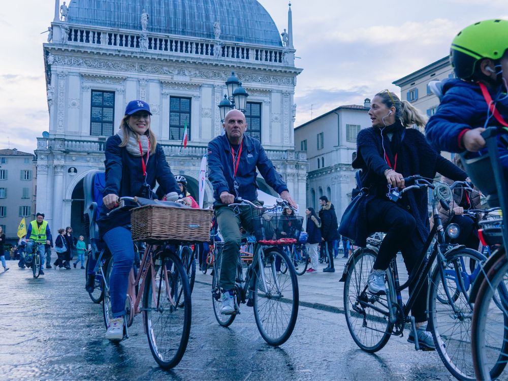 Gruppo di uomini e donne in bici in piazza Loggia