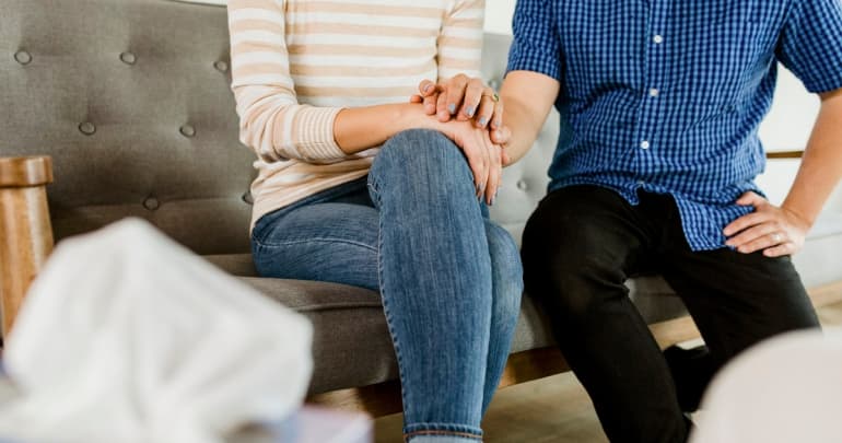 Couple holding hands sitting on a sofa