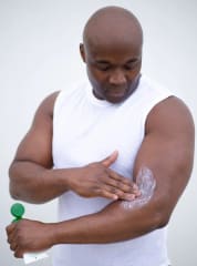 A man applying massage lotion to his left arm