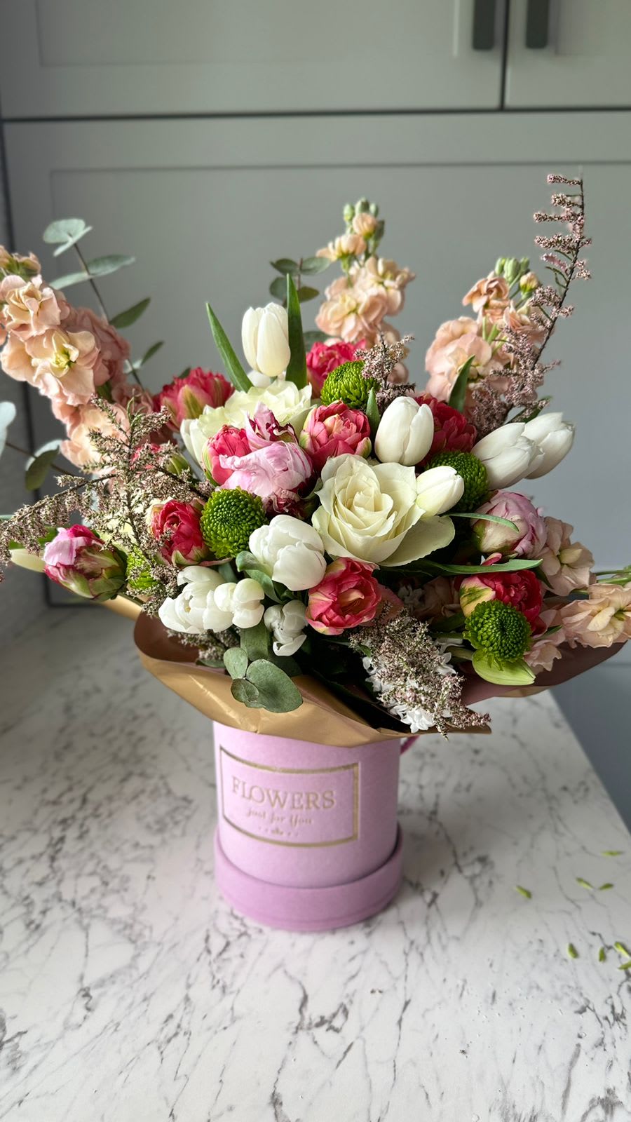 Colourful bouquet of yellow roses and carnations in a decorative red vase