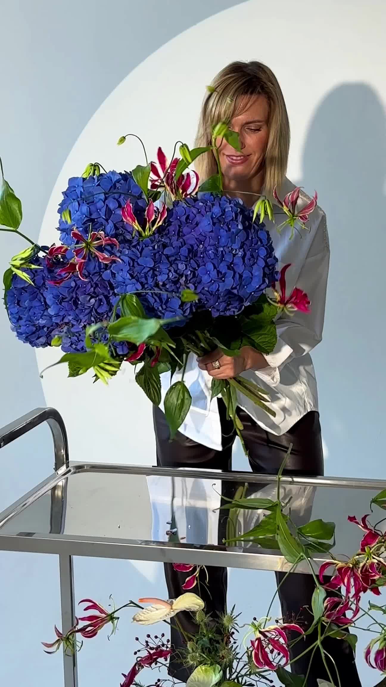 Person arranging a bouquet of blue hydrangeas during a floristry workshop