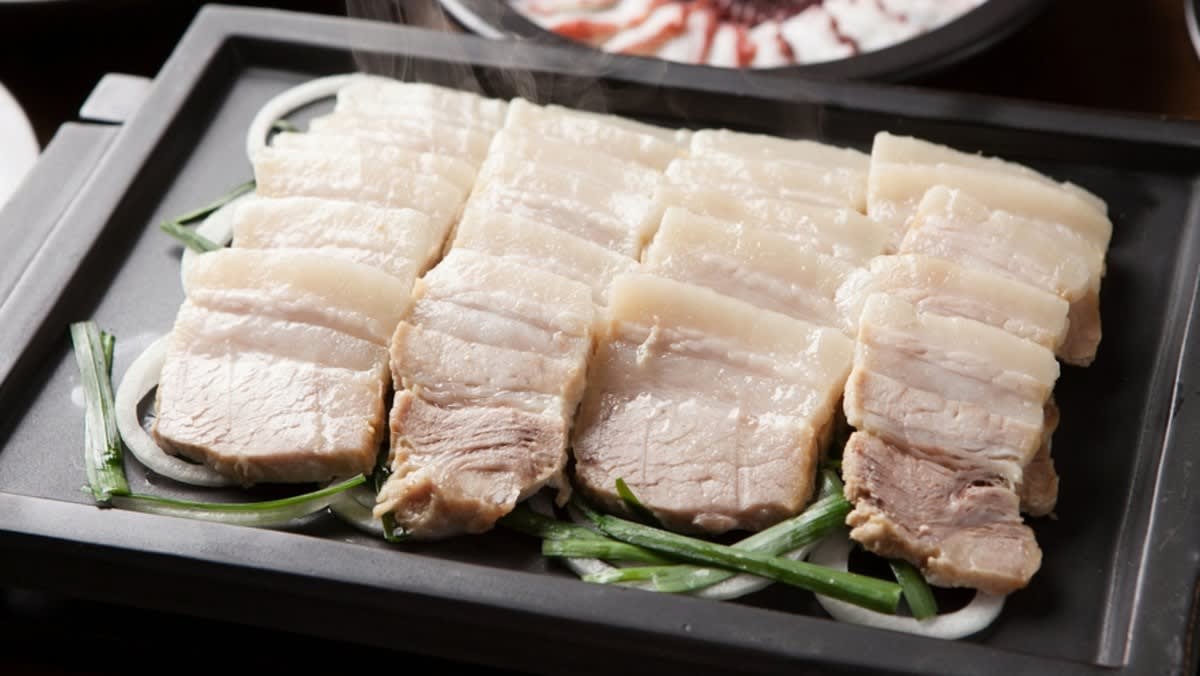 Đĩa thịt heo luộc thái mỏng, trắng mềm, ăn kèm rau sống