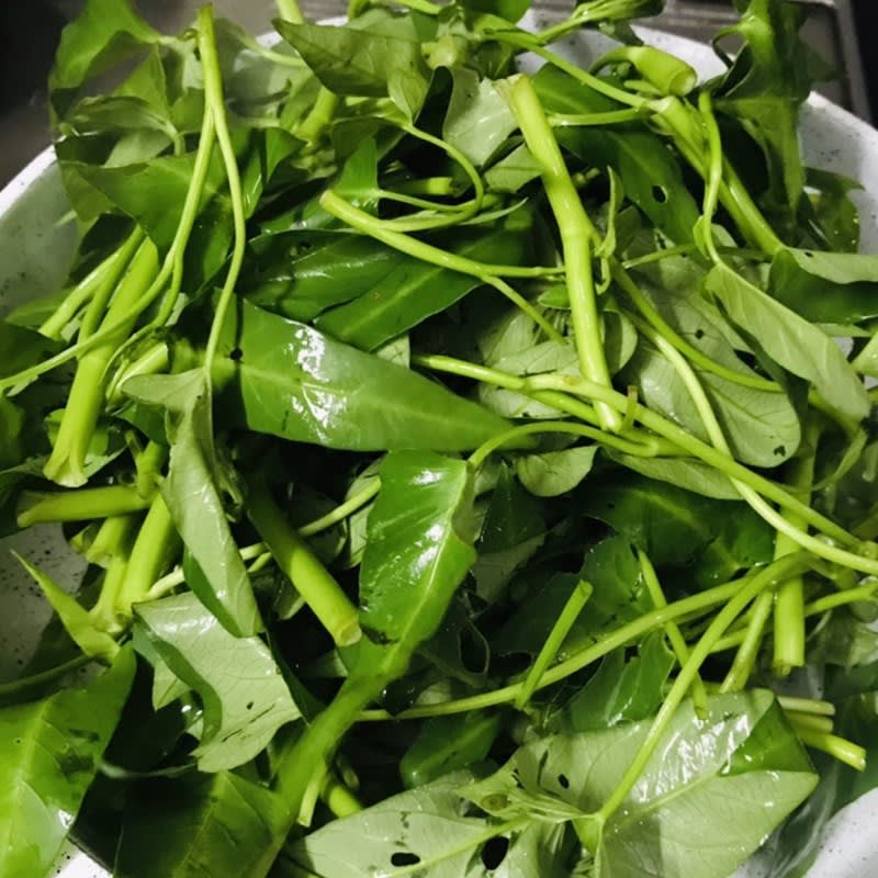 Xào rau muống với tỏi trên lửa lớn trong chảo