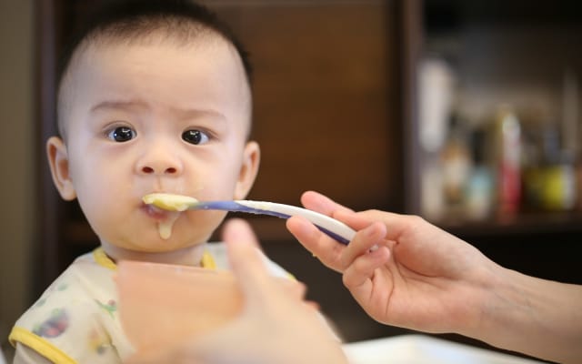 Bé được mẹ đút thìa bột trong bữa ăn dặm