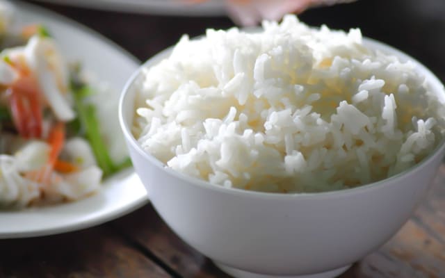 Bát cơm trắng đặt cạnh rau và thịt trong bữa ăn giảm cân