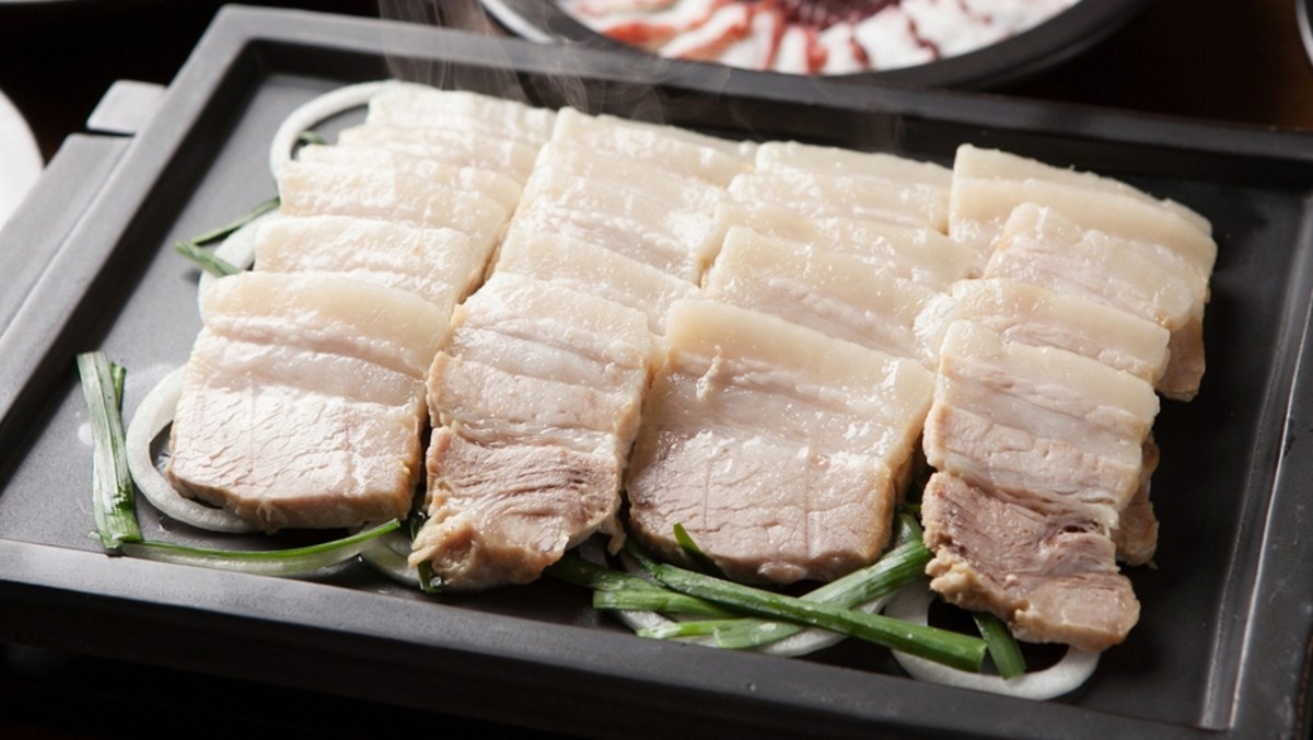 Đĩa thịt heo luộc thái mỏng, trắng mềm, ăn kèm rau sống