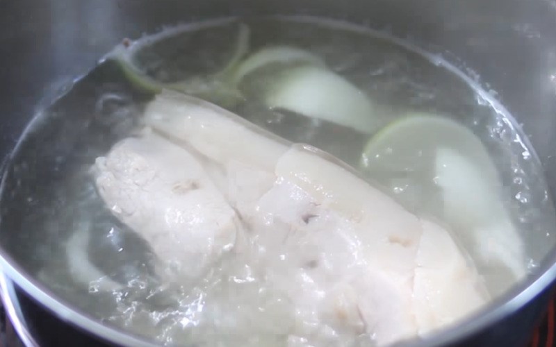 Nồi thịt heo đang luộc cùng hành tím và gừng