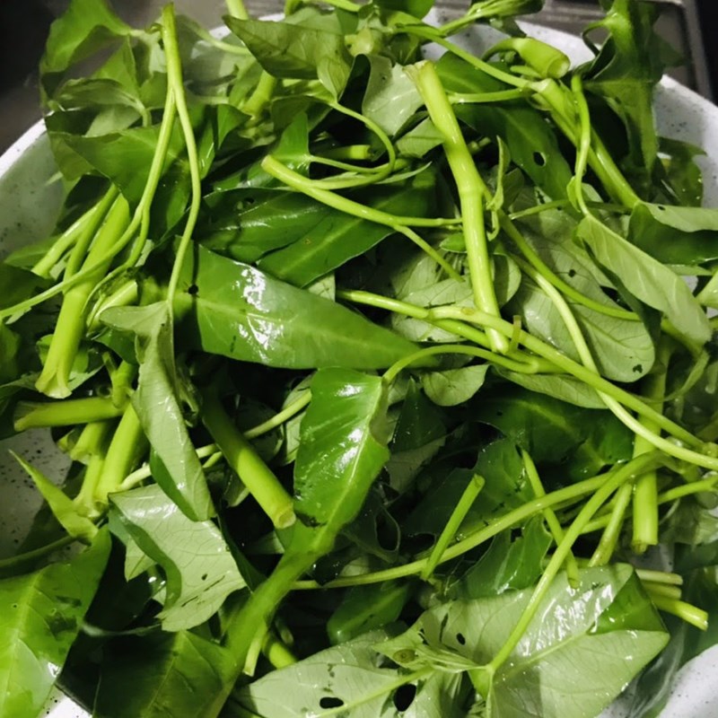 Xào rau muống với tỏi trên lửa lớn trong chảo