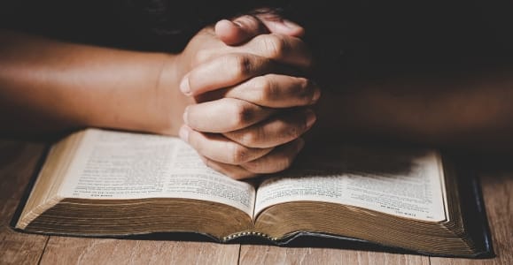 clasped hand on bible = Photo ©jcomp freepik.com