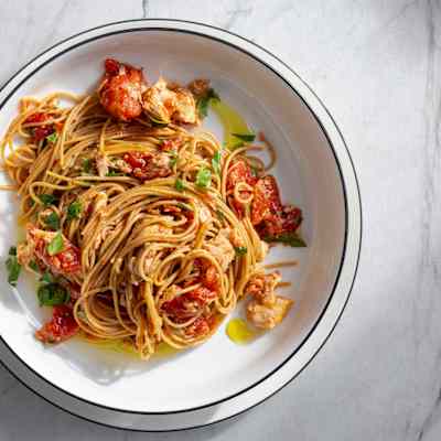 a white bowl of Spaghetti al Tonno sits on a marble table