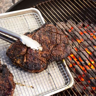 spiced rubbed steak being removed from charcoal grill