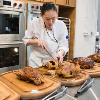 A test cook carving ducks on a cutting board