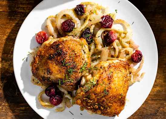 Roasted Chicken Thighs with Grapes and Fennel on a white plate on a wooden table