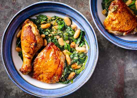 Skillet-Roasted Chicken with Garlicky Spinach and Beans on a plate with a blue edge