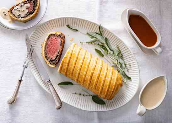 Beef Wellington wrapped in golden pastry on a serving platter