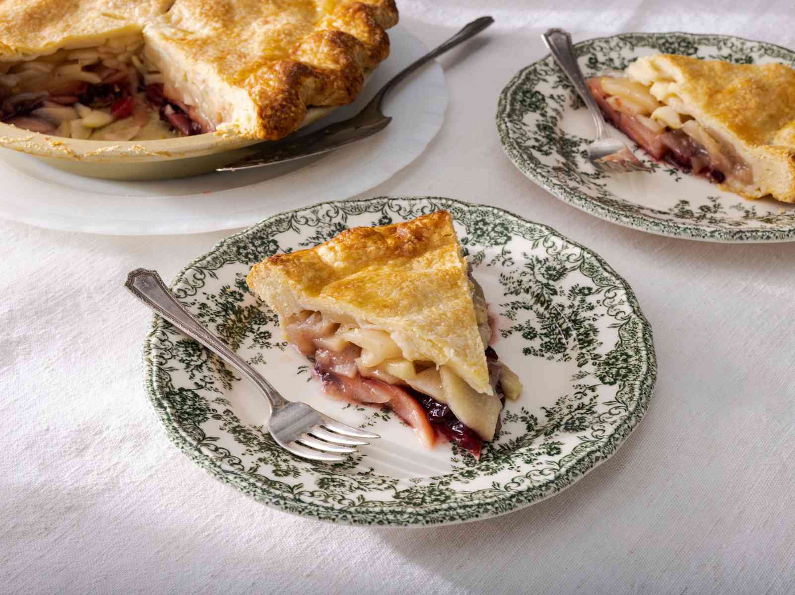 Slice of pie on a plate with a fork, whole pie in background