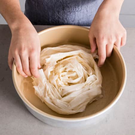 placing phyllo strips in cake pan until pan is filled with large spiral shape