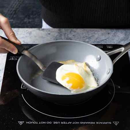 A test cook uses a compact spatula to flip an egg frying in an 8-inch skillet. 