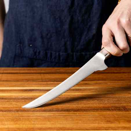 A boning knife is pressed against a cutting board, with no flex.