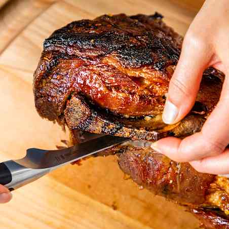 A boning knife is used to cut out the bone of a roast pork shoulder.