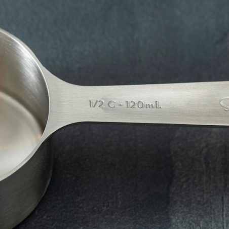 Close-up of the handle of a dry measuring cup with ½ c - 120 mL etched into it 