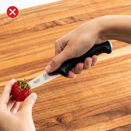 Close-up of hulling a strawberry with a knife that has a big, long handle