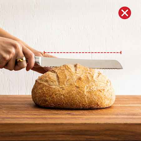 A short bread knife struggles to cut neatly through an oversized rustic loaf.