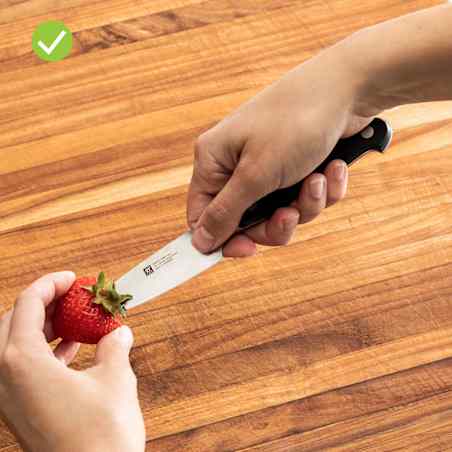 Close-up of hulling a strawberry with a knife that as petite handle