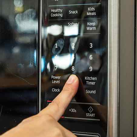 The shiny black control panel of a microwave that shows glares and fingerprints