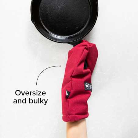 Person wearing a red oven mitt gripping the handle of a black cast-iron skillet.